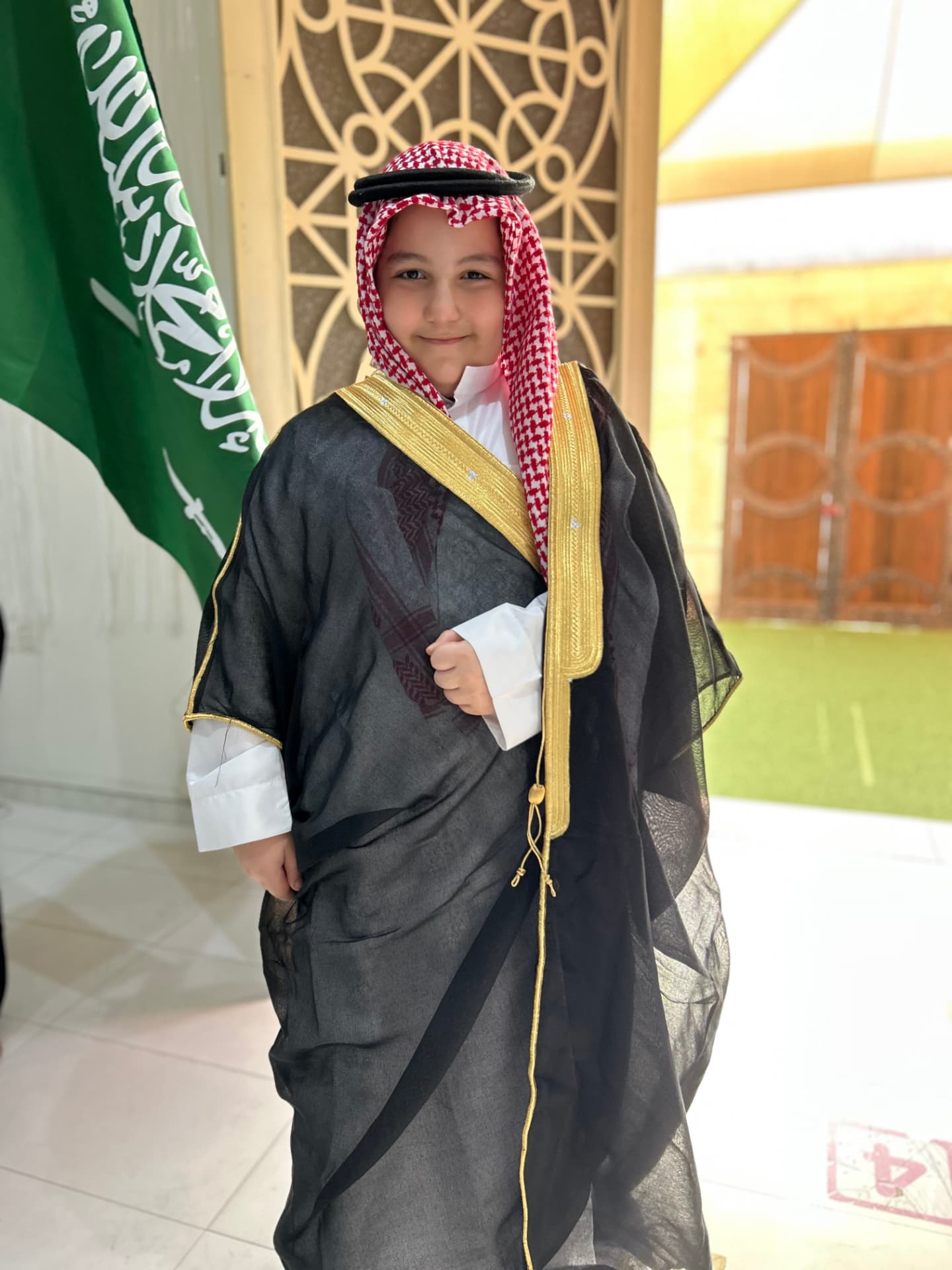 ARWA pupil in traditional Saudi dress beside the national flag